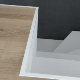 Fragment podłogi z paneli imitujących drewno, z widocznym wejściem do piwnicy lub schowka wykończonym białymi listwami.