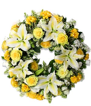 Wieniec pogrzebowy z białych lilii i żółtych róż, otoczony drobnymi białymi kwiatami, na białym tle.