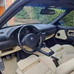 Wnętrze kabrioletu BMW Z3 z jasną skórzaną tapicerką, widok z zewnątrz pojazdu, ukazujący deskę rozdzielczą, kierownicę i fotele po zabiegach pielęgnacyjnych.