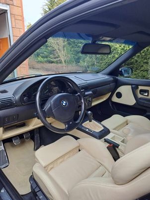 Wnętrze kabrioletu BMW Z3 z jasną skórzaną tapicerką, widok z zewnątrz pojazdu, ukazujący deskę rozdzielczą, kierownicę i fotele po zabiegach pielęgnacyjnych.