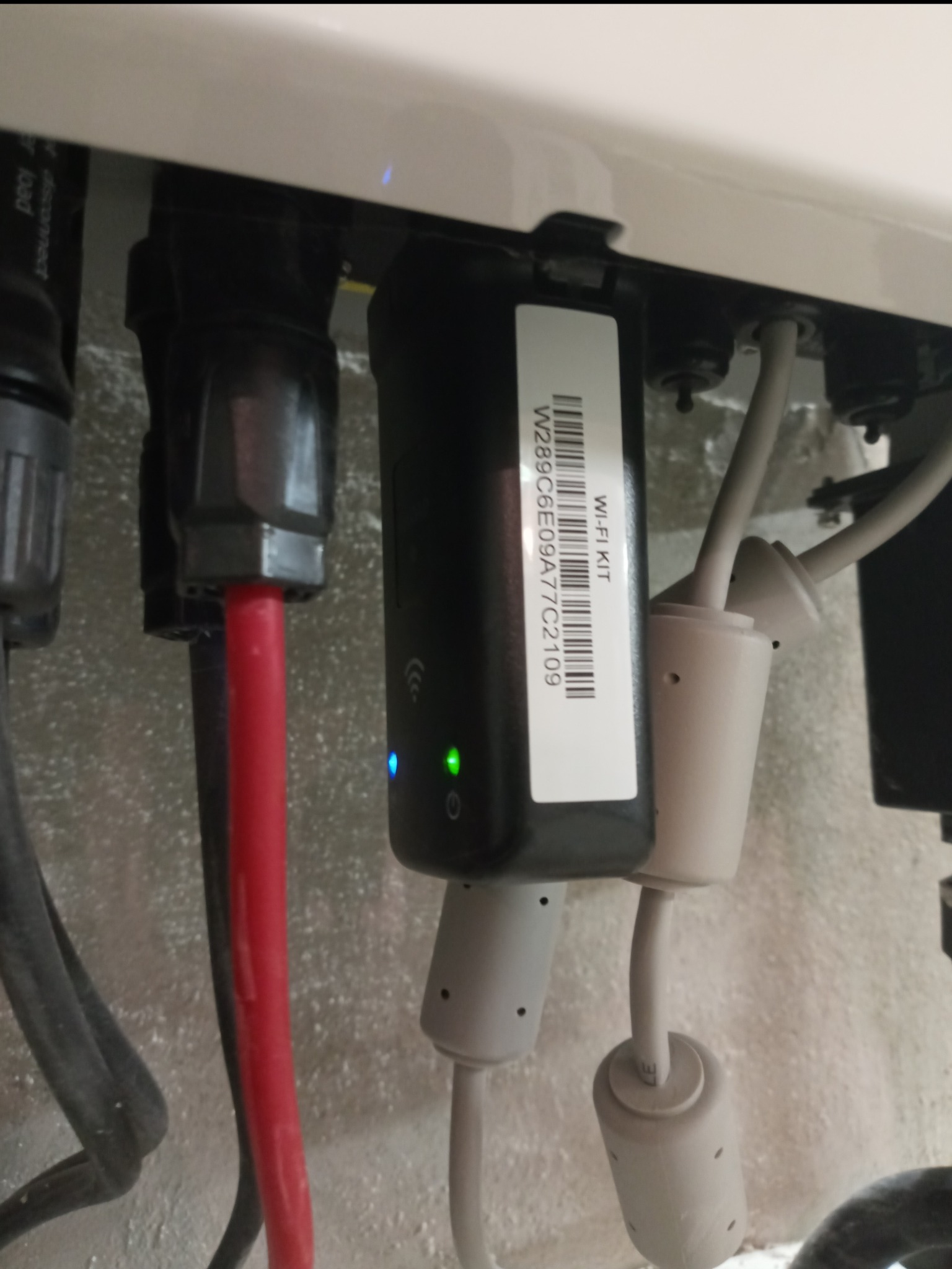 Szczegółowe ujęcie podłączenia modułu Wi-Fi Kit z kodem kreskowym W289C6E09A77C2109 do instalacji, widoczne złącza i przewody w kolorach czerwonym i szarym, z diodami LED sygnalizującymi pracę...