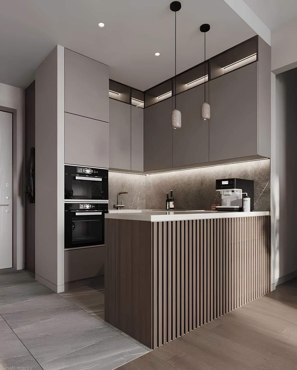 Nowoczesna kuchnia w odcieniach szarości z wyspą wykończoną pionowymi listwami, oświetleniem LED pod szafkami i wiszącymi lampami o marmurkowej fakturze.