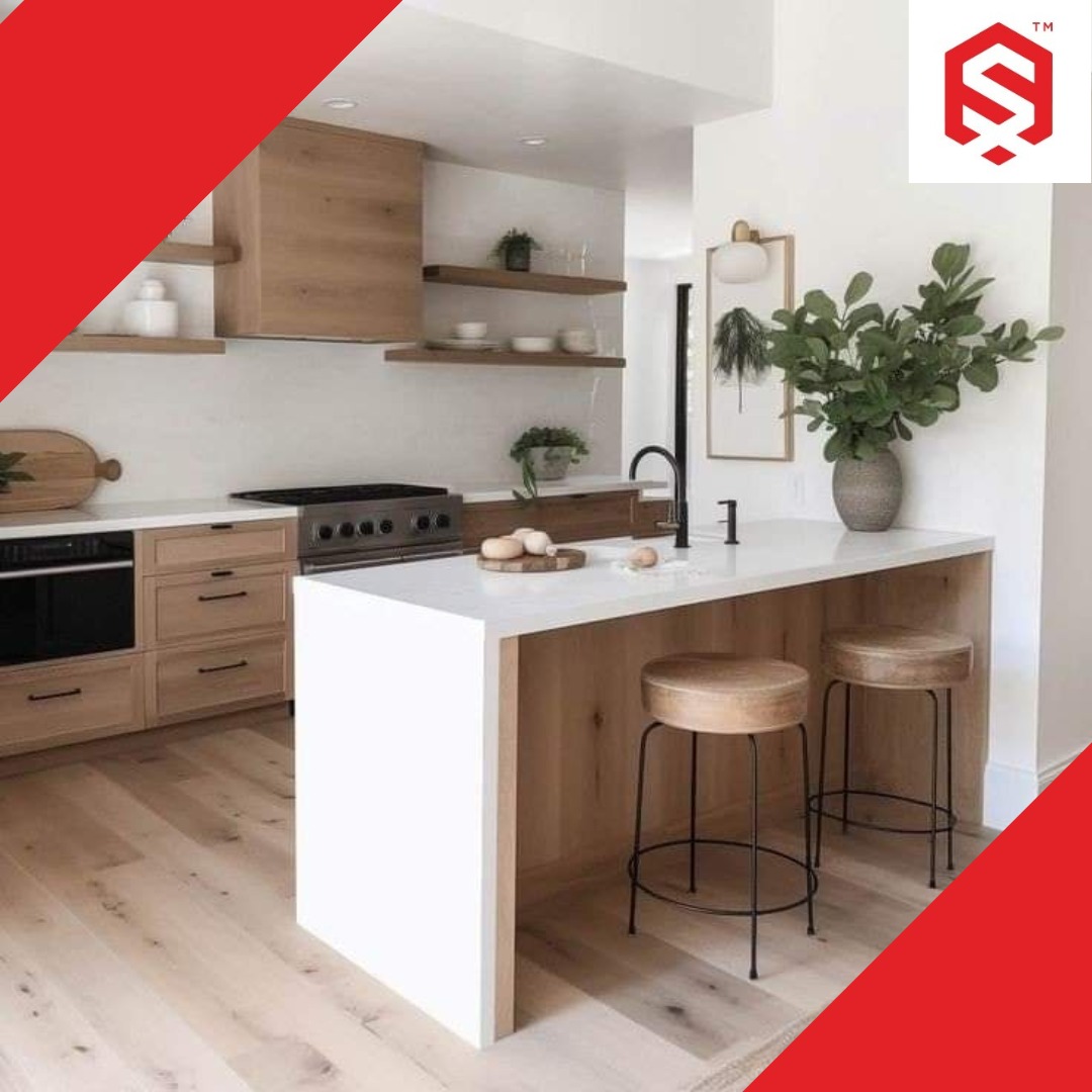 Jasna kuchnia z drewnianymi szafkami, białym blatem i wyspą, uzupełniona o drewniane hokery i minimalistyczne dekoracje.