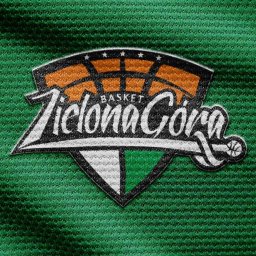DOBRZY.PL - Wyhaftowane logo drużyny koszykarskiej 'Zelona Góra' na zielonej, teksturowanej tkaninie. Logo zawiera elementy graficzne takie jak kosz, piłka i gwiazdy.