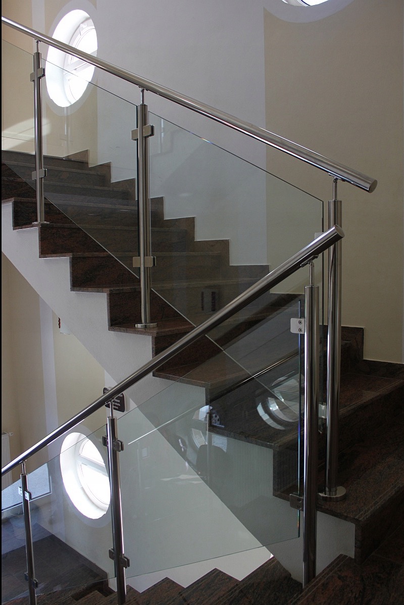 Szklana balustrada ze stali nierdzewnej na marmurowych schodach, okrągłe okno w tle. Nowoczesny design, eleganckie wykończenie.