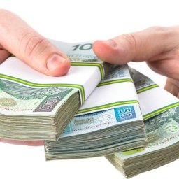 MONIKA FINANSE - Dłonie w mankietach koszuli prezentują trzy spięte pakiety banknotów 100 i 50 złotowych na białym tle.