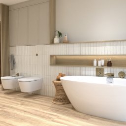 Pracownia Arch. Wnętrz M. Kulczykowski - Nowoczesna łazienka z wolnostojącą białą wanną, bidetem i toaletą, drewnianą podłogą i szafkami wiszącymi w beżowym kolorze, oświetlona półka z akcesoriami i roślinami.