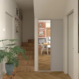 Wnętrze domu: schody z drewna, parkiet w jodełkę, rośliny doniczkowe i przesuwne drzwi, które odsłaniają jadalnię z ceglaną ścianą i kominkiem.