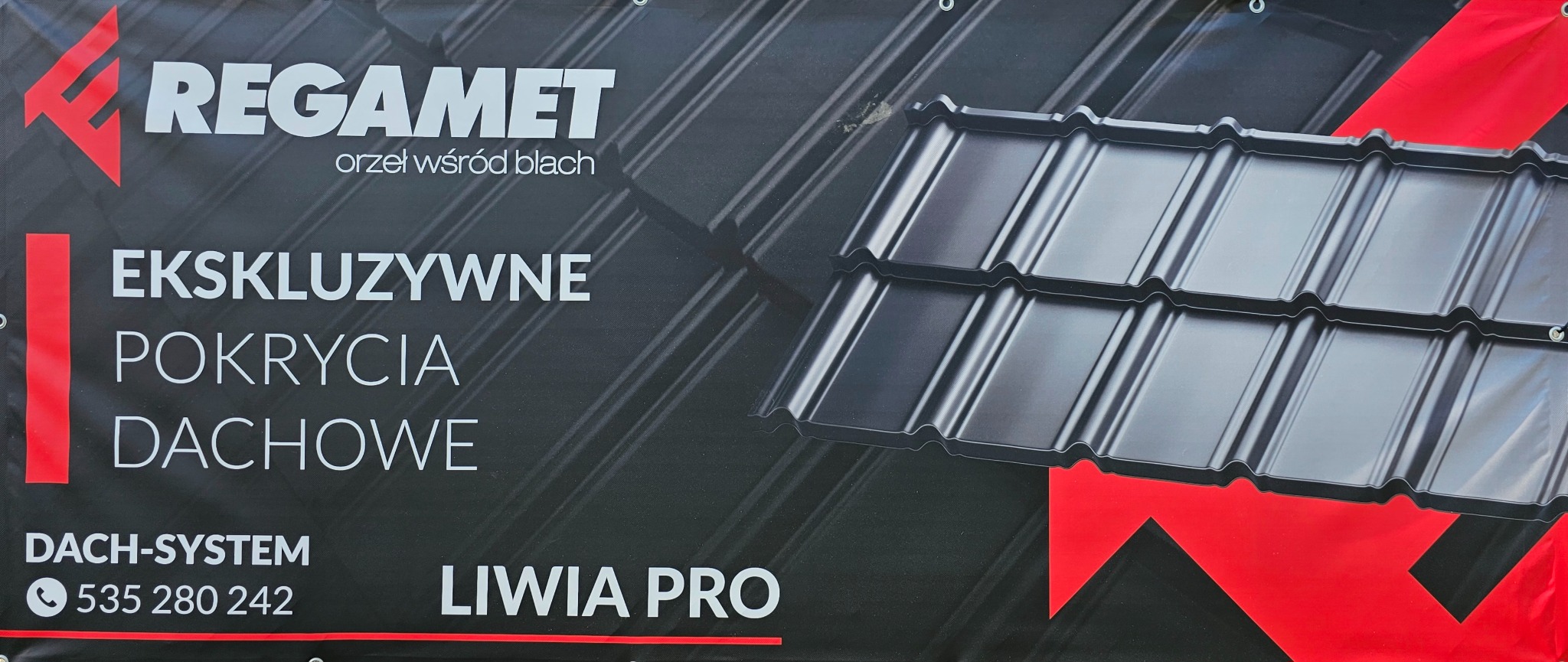 Baner reklamowy z czarną blachodachówką REGAMET Liwia PRO, hasłem 'Ekskluzywne pokrycia dachowe' i numerem telefonu.