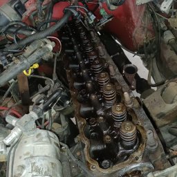 QuickService Mateusz Góra - Otwarty silnik samochodowy z widocznymi sprężynami zaworowymi i przewodami, z bliska, w trakcie naprawy.