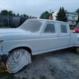 QuickService Mateusz Góra - Biały pickup Ford F-350 po szpachlowaniu, przygotowany do lakierowania, z maskowaniem folią i materiałem, na zewnątrz warsztatu.