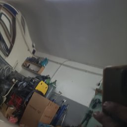 QuickService Mateusz Góra - Odbicie w karoserii samochodu, ukazujące warsztat z narzędziami, częściami zamiennymi i kartonami, oświetlony jarzeniówką.