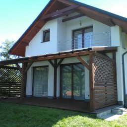 Zadaszenie tarasu pokryte poliwęglanem, podłoga z deski tarasowej ryflowenej, ażurowa delikatna zabudowa.