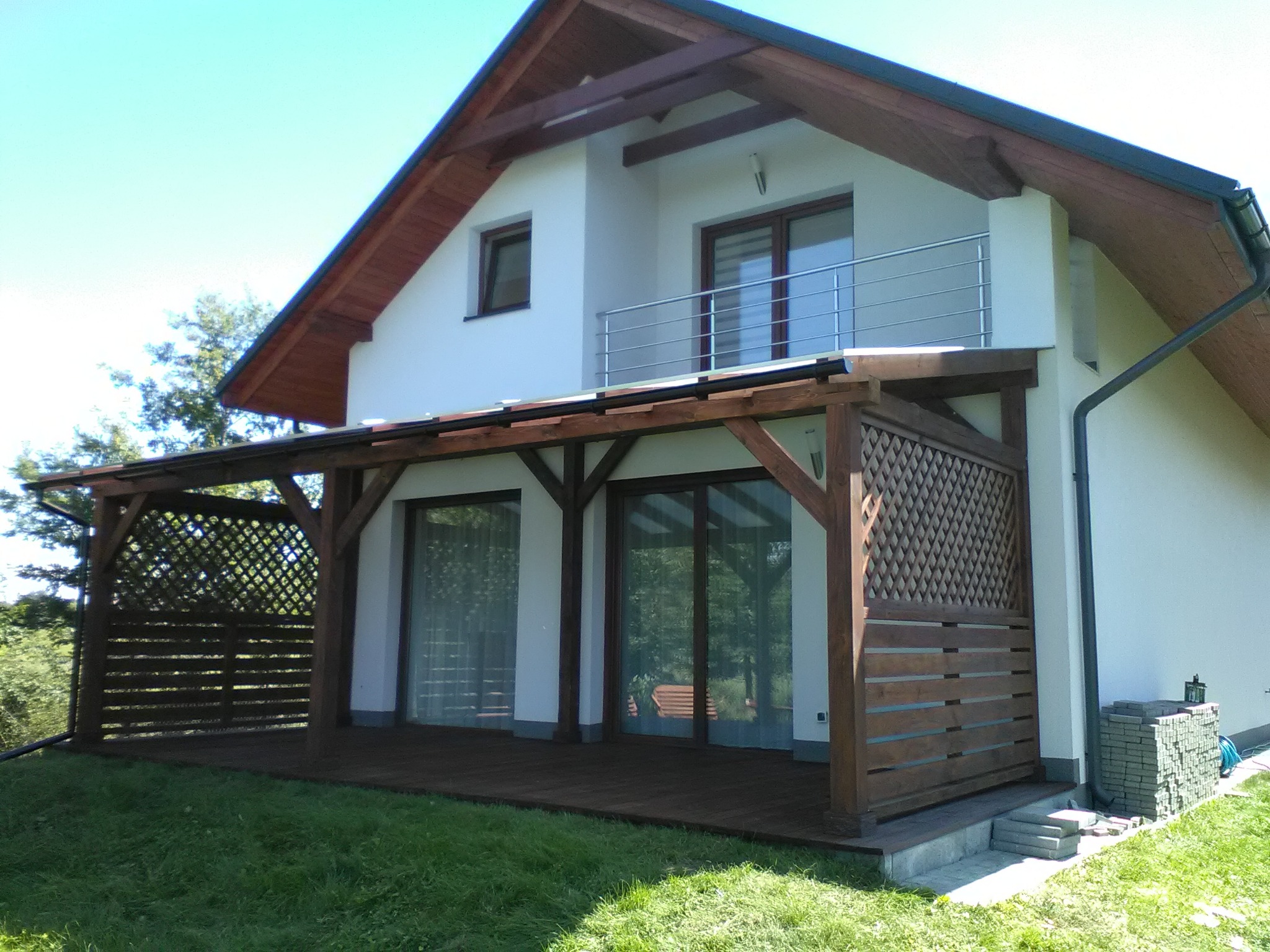 Zadaszenie tarasu pokryte poliwęglanem, podłoga z deski tarasowej ryflowenej, ażurowa delikatna zabudowa.