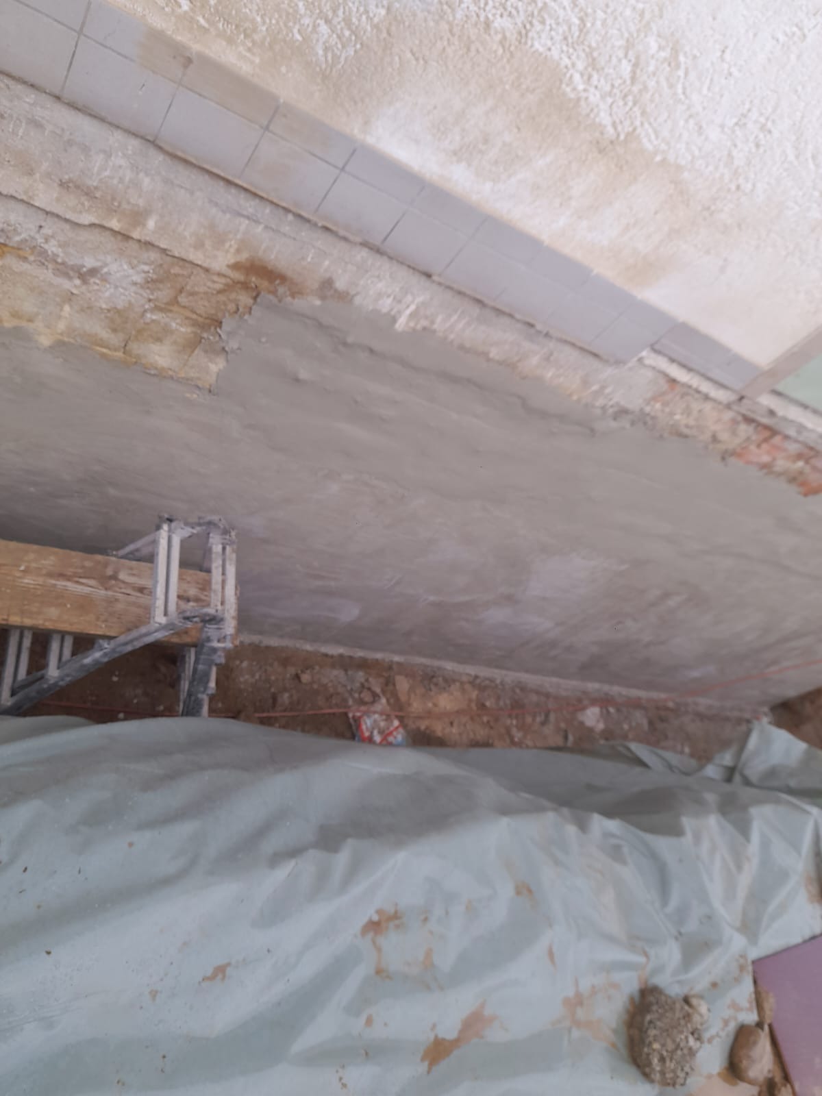 Prace przygotowawcze do izolacji fundamentów w Żegocinie: widok na zabezpieczony wykop, częściowo otynkowane ściany z cegły i fragment rusztowania.