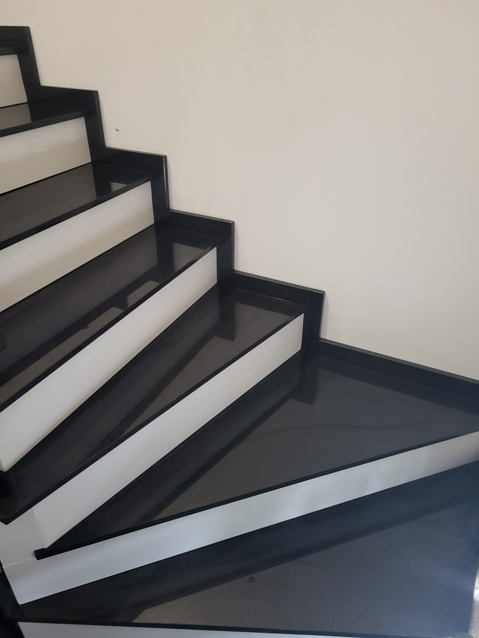 Nowoczesne schody z czarnego kamienia z białymi podstopnicami, widok z góry, minimalistyczny design.