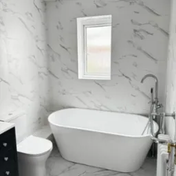 Wykończona łazienka z wanną wolnostojącą, umywalką z szafką w kolorze ciemnego grafitu i marmurowymi płytkami na ścianach i podłodze.