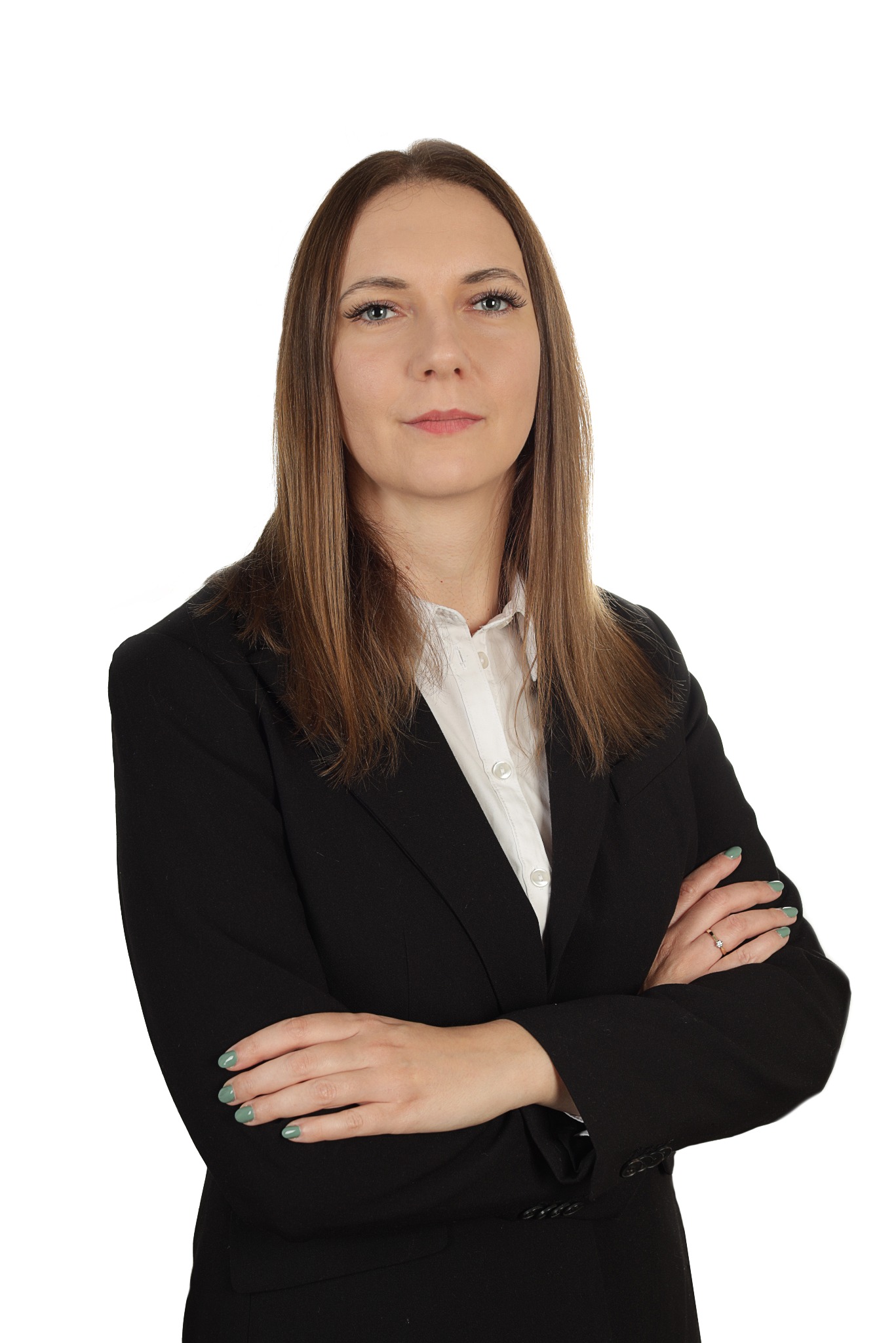 Portret kobiety w czarnym żakiecie i białej koszuli, z założonymi rękami i pierścionkiem, na białym tle.