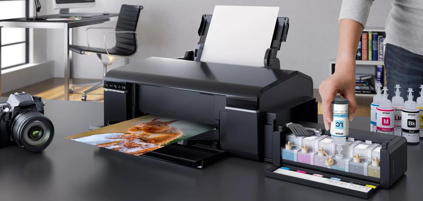 Uzupełnianie tuszu w drukarce atramentowej, obok butelki z tuszem i wydrukowane zdjęcie wiewiórki.