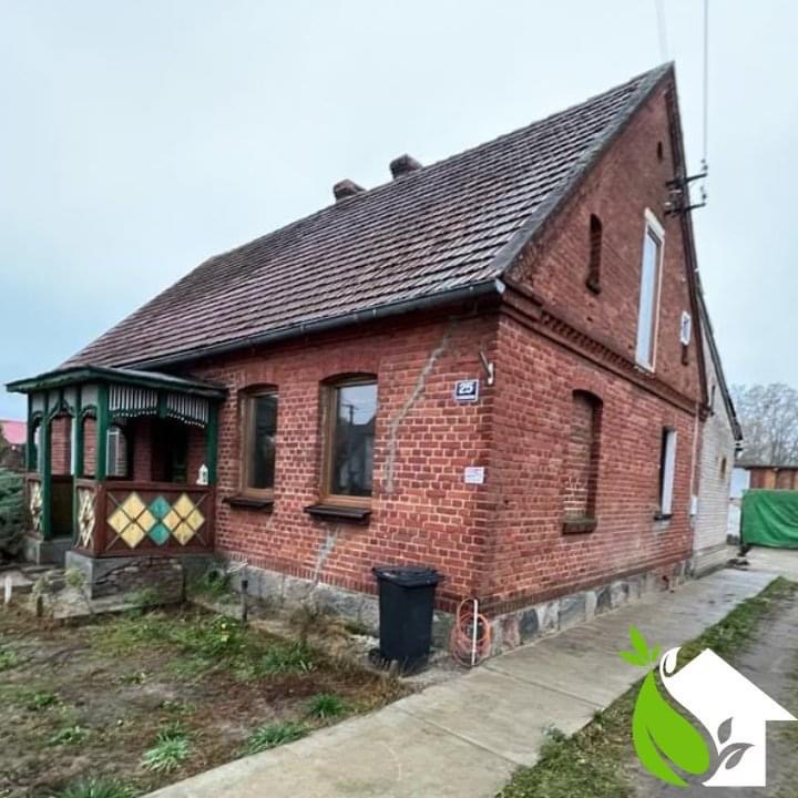 Ceglany dom jednorodzinny przed termomodernizacją, widoczny numer posesji 25 i częściowo otynkowana ściana szczytowa.