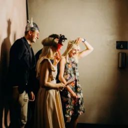 Grupa czterech osób w przebraniach pozuje do zdjęcia w fotobudce: mężczyzna w hełmie wikinga, kobieta w sukience w kwiaty z koroną na głowie, kobieta w beżowej sukience z opaską na głowie...