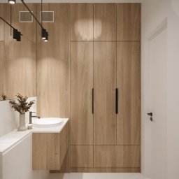 AW Architektura Wnętrz Agata Wilk - Nowoczesna łazienka w Gdyni z drewnianą zabudową meblową, minimalistyczną umywalką i czarnymi akcentami oświetleniowymi.