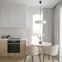 Jasna kuchnia z drewnianymi szafkami, białymi górnymi szafkami i okrągłym stołem z dwoma krzesłami, minimalistyczna lampa wisząca i dekoracyjna trawa pampasowa w szklanym wazonie na stole.