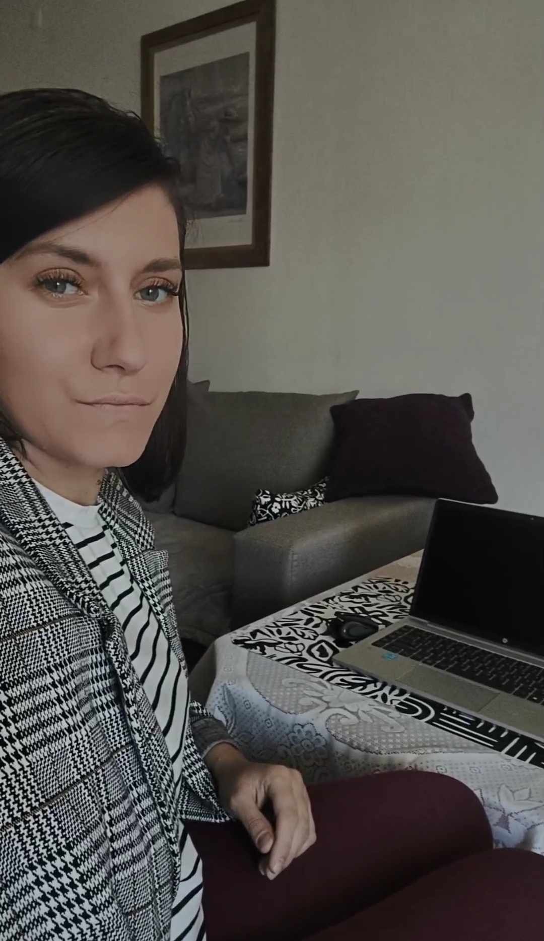 Kobieta w marynarce w kratę siedzi przy stole z laptopem, prawdopodobnie podczas konsultacji online.