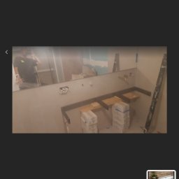 EKODOM REMONTY-WYKOŃCZENIA - Łazienka w trakcie prac: przygotowane pod blaty szafek umywalkowych, widoczne puszki elektryczne, niezabezpieczone przewody, oraz zapas płytek w oryginalnych opakowaniach.