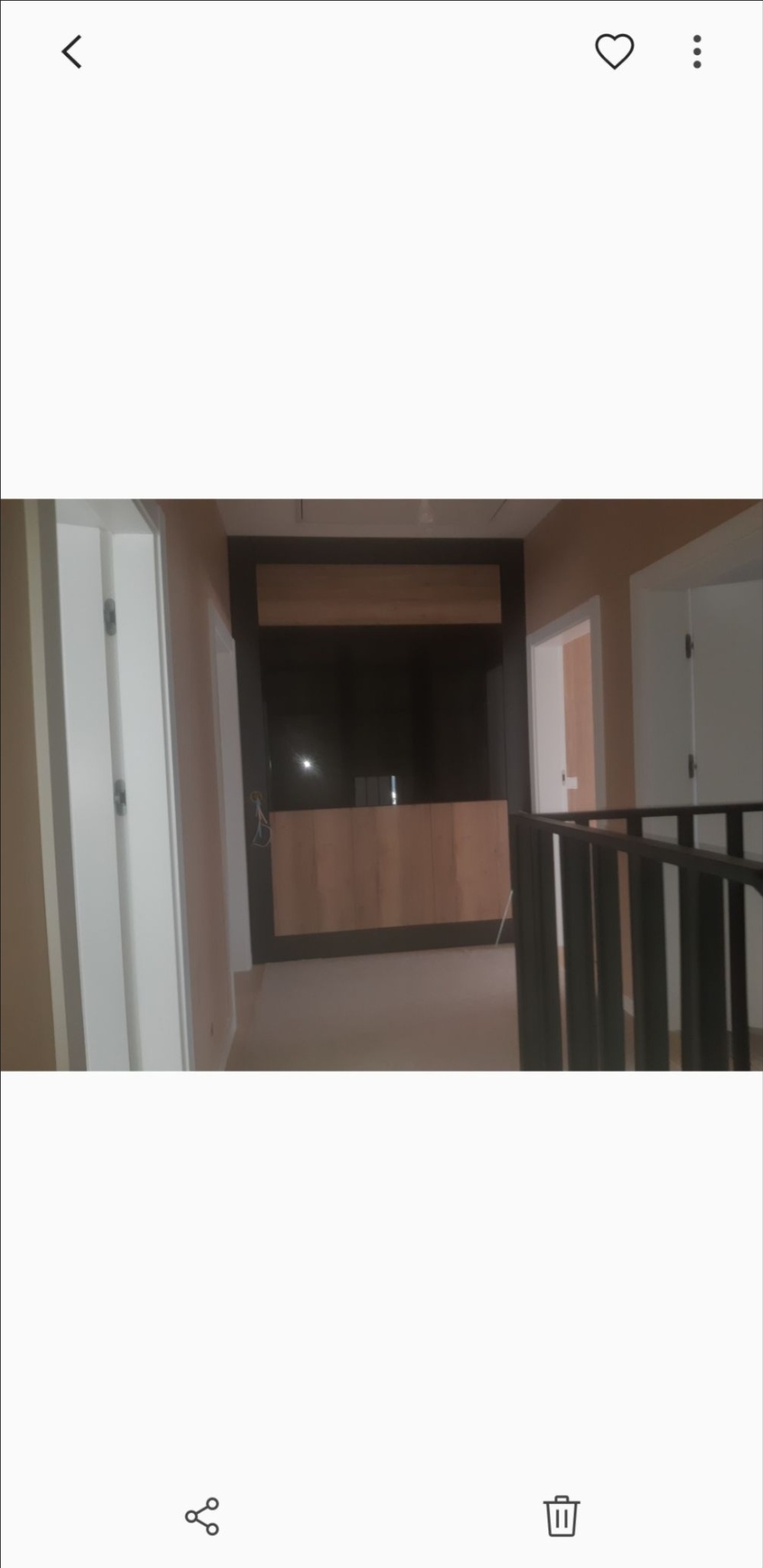 Korytarz w trakcie wykańczania, zabudowa meblowa z drewnianymi frontami, widoczne drzwi i fragment balustrady.