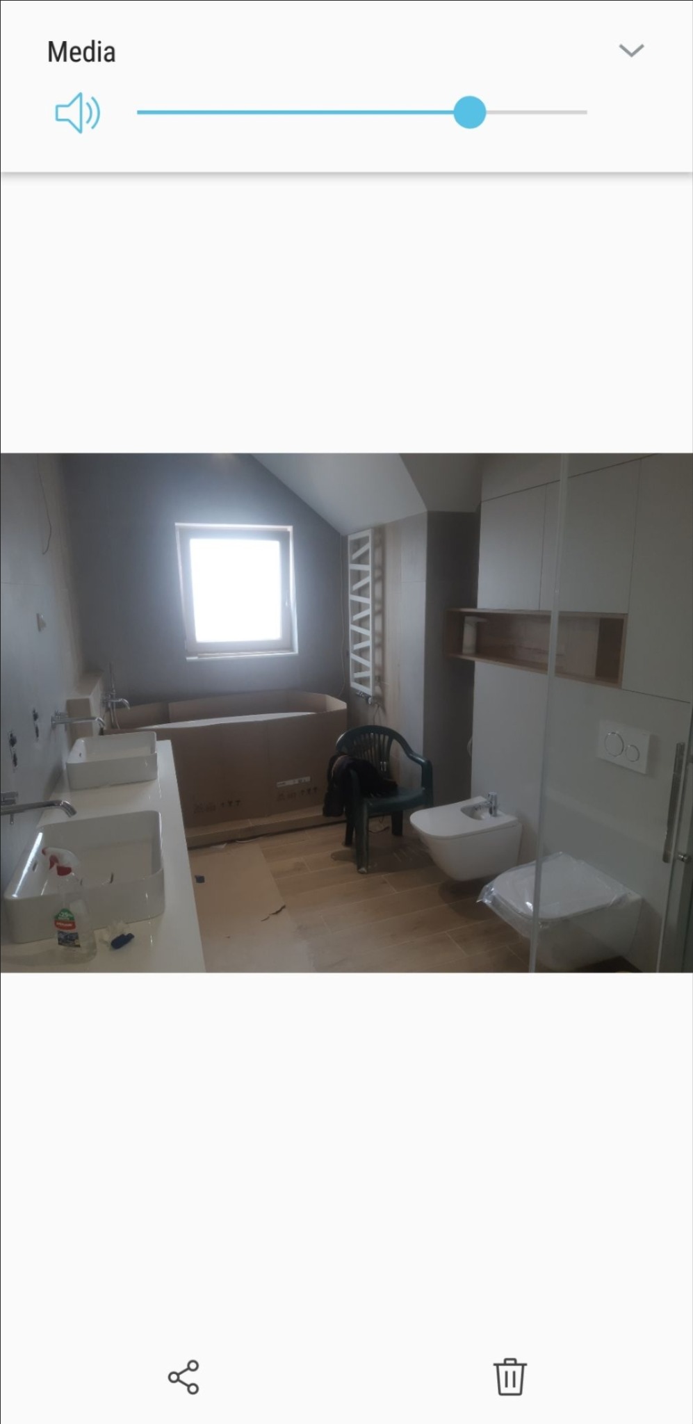 Łazienka w trakcie prac wykończeniowych: podwójna umywalka, bidet i toaleta zamontowane, wanna w kartonowym opakowaniu, grzejnik drabinkowy i płytki podłogowe ułożone.