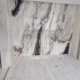 Funt BUD - Wykończona łazienka z marmurowymi płytami na ścianach i podłodze. Na suficie widoczny fragment świeżo położonej gładzi. Minimalistyczny design.