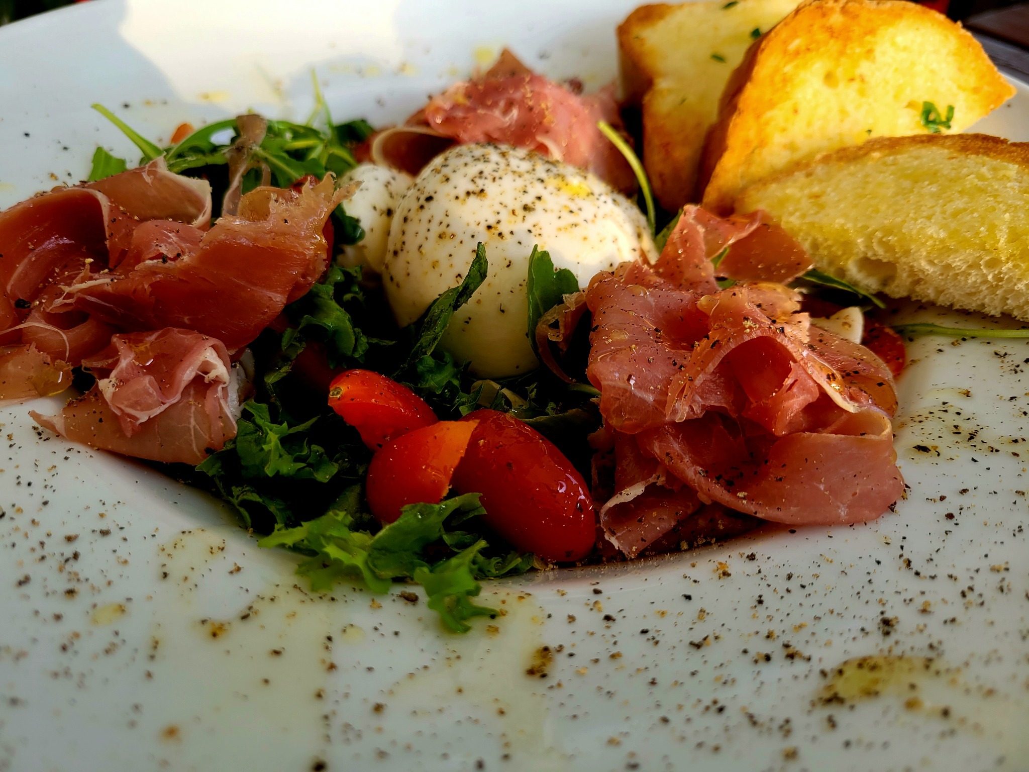 Sałata z burratą, pomidorkami koktajlowymi, szynką prosciutto crudo i oliwą z oliwek