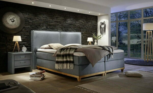 Elegancka sypialnia z łóżkiem kontynentalnym w odcieniach szarości, drewniana rama, kamienna ściana i lampki nocne w stylu skandynawskim.
