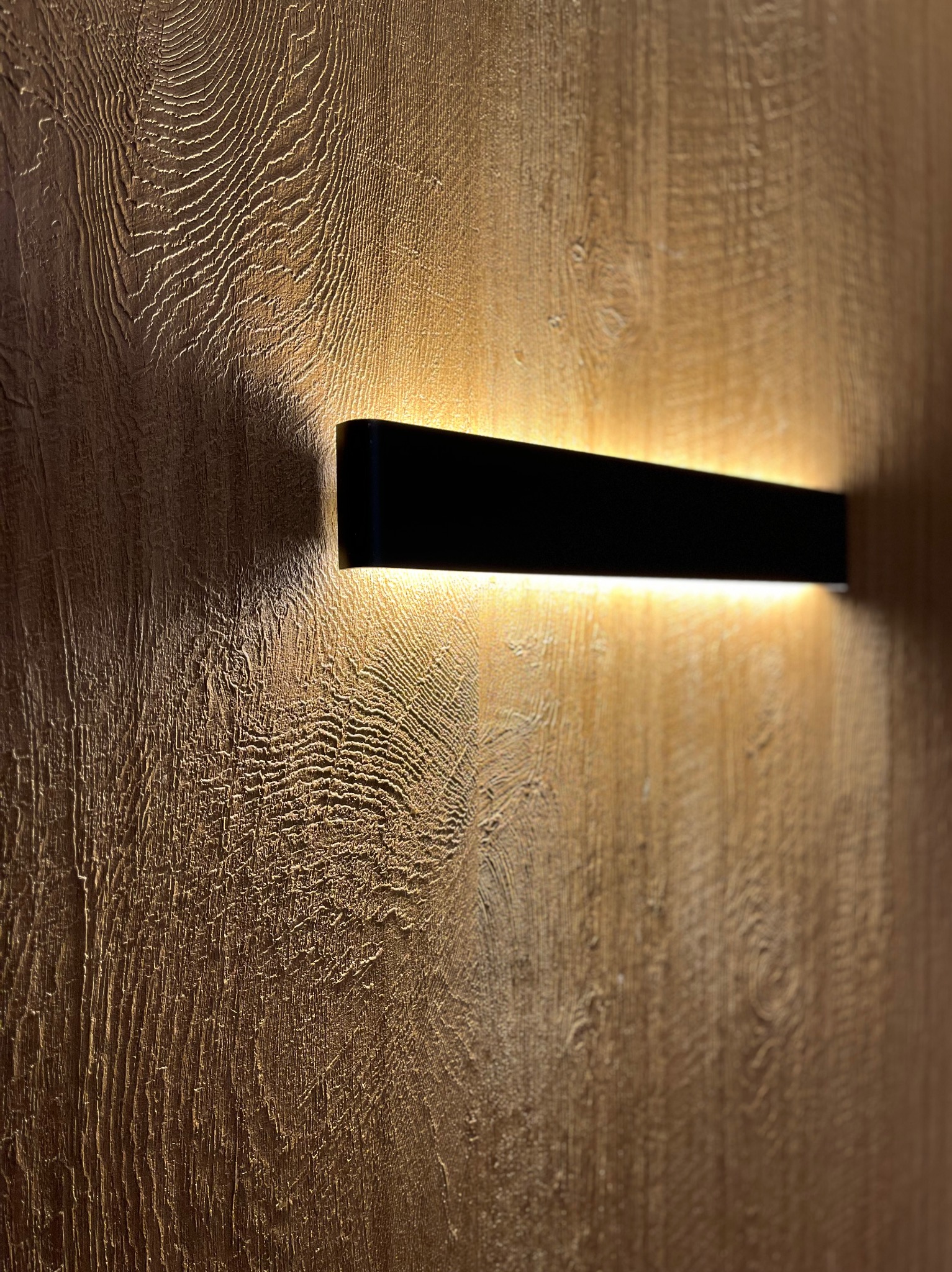 Strukturalna ściana imitująca drewno z zamontowanym, podświetlanym, czarnym panelem LED.