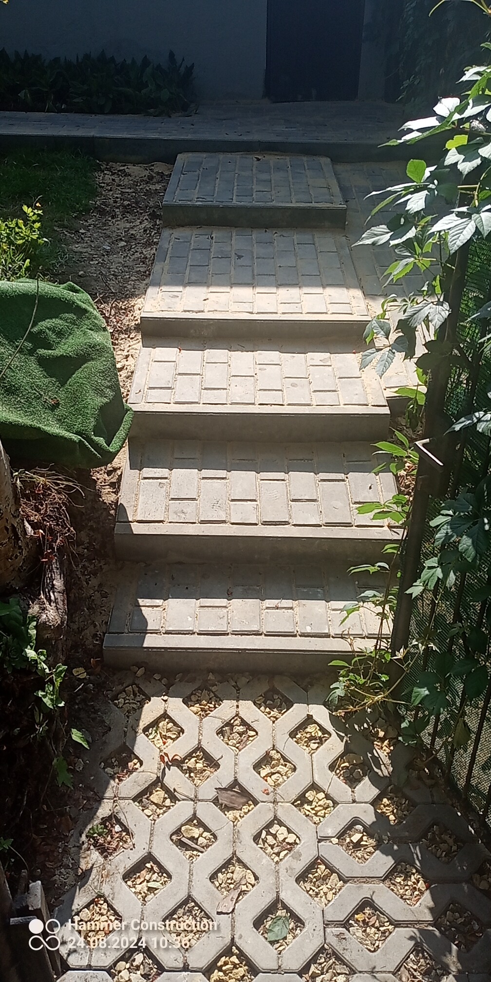 Betonowe schody zewnętrzne z ażurowymi płytami u podstawy, otoczone zielenią.