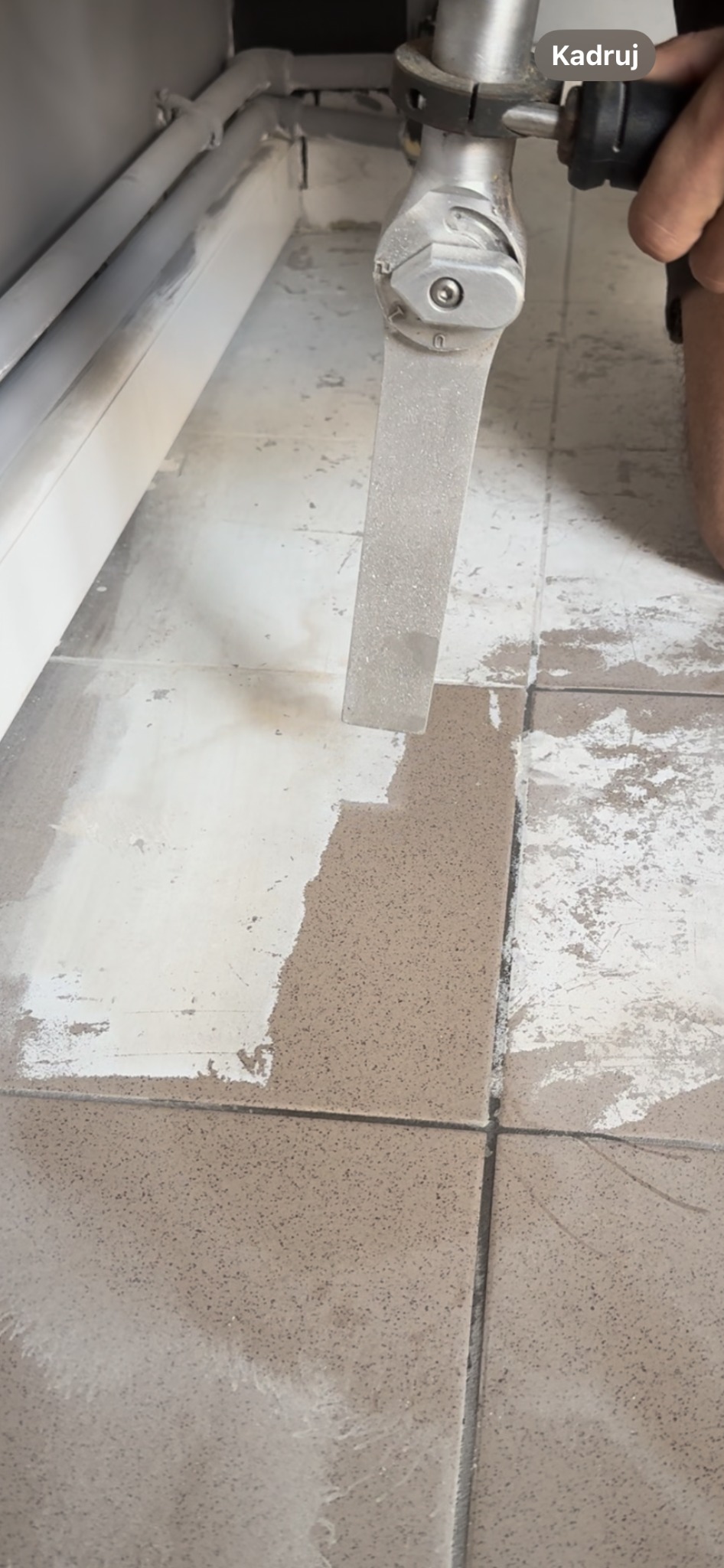 Szlifowanie powierzchni płytek podłogowych za pomocą szlifierki kątowej z metalową tarczą, widoczne ślady po obróbce i pozostałości pyłu.