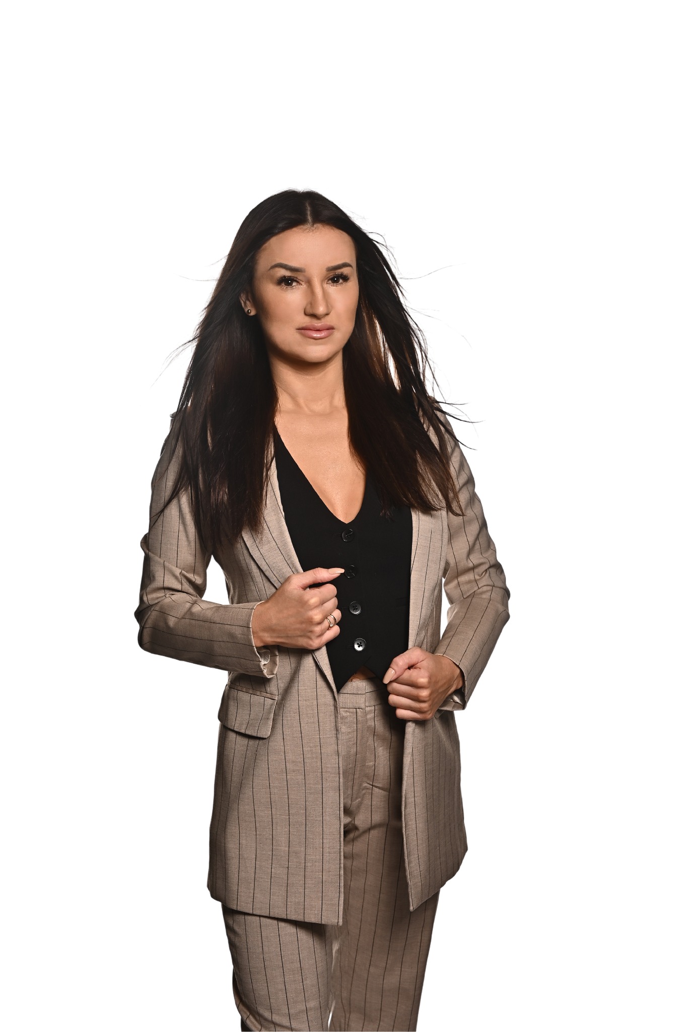 Kobieta w beżowym garniturze w prążki i czarnej kamizelce, prezentująca się jako doradca finansowy w Toruniu, z delikatnym uśmiechem i rozwianymi włosami.