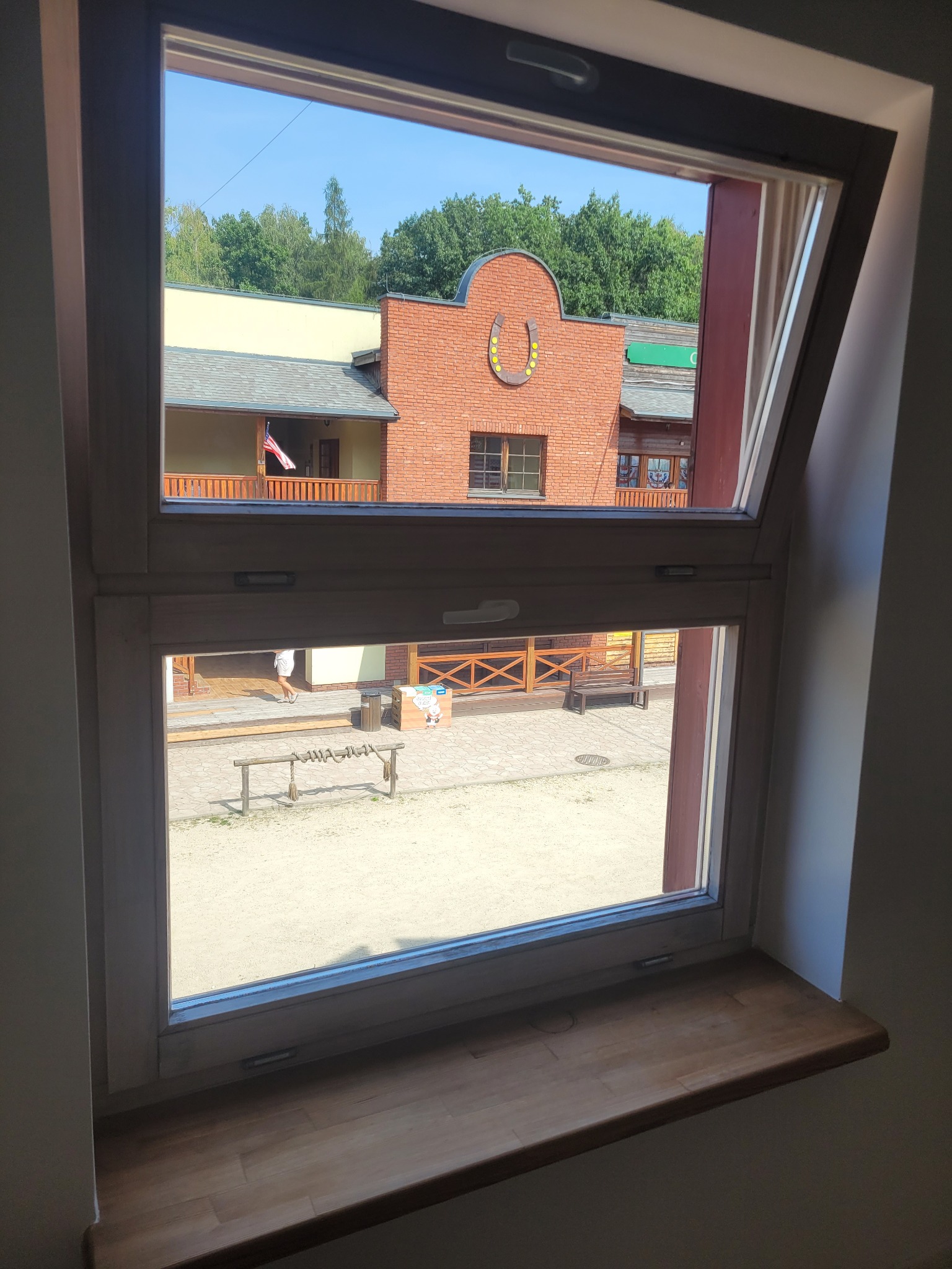 Widok z okna na stylizowane miasteczko westernowe z ceglanymi budynkami i dekoracyjnym podwórkiem.