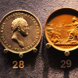 solian400 - Dwie okrągłe, metalowe medale z wizerunkami i napisami, umieszczone na ciemnym, teksturowanym tle, ponumerowane 28 i 29.