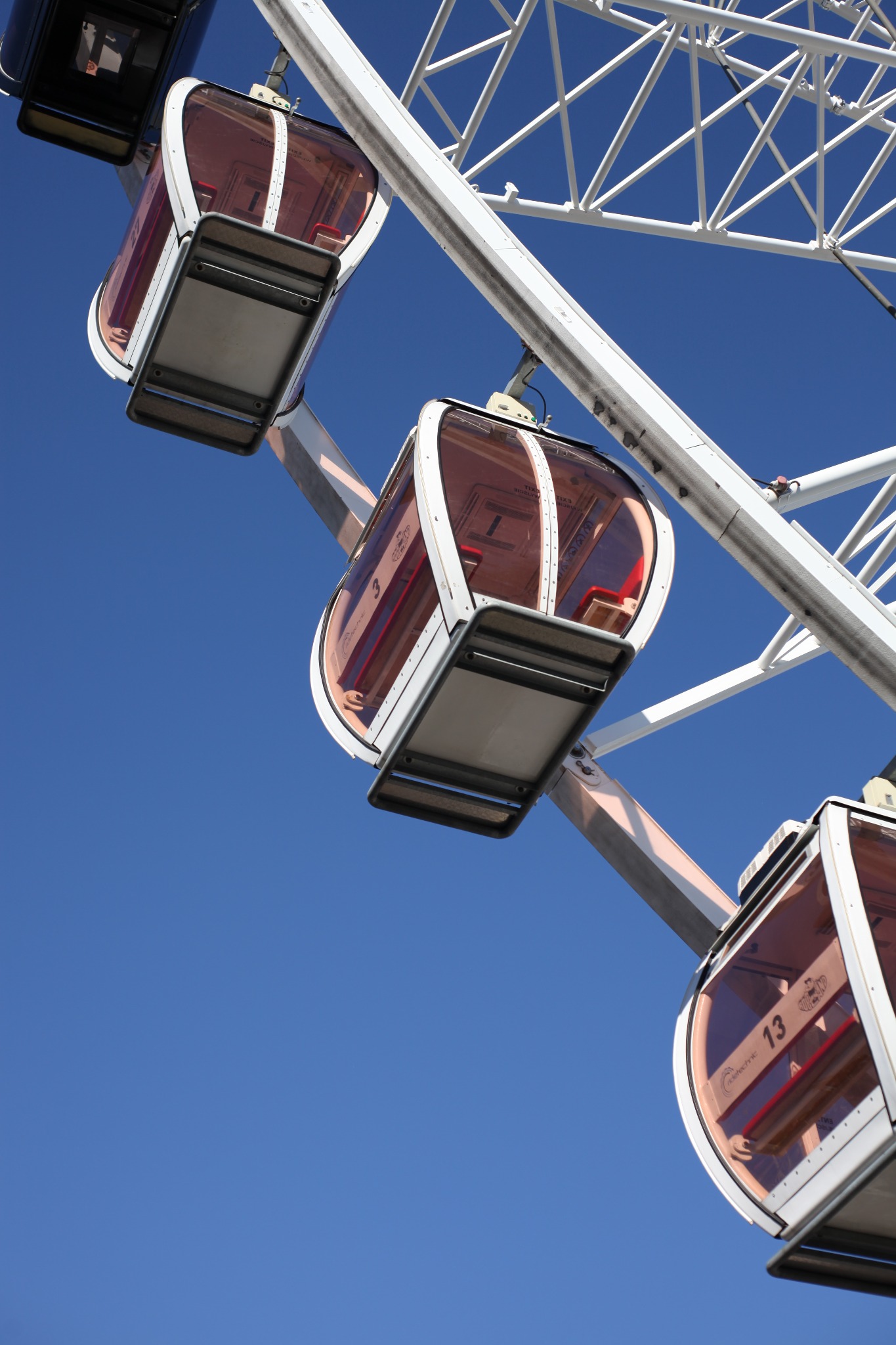 Kabinowe koło widokowe z numerem 13 na tle błękitnego nieba, widoczne elementy konstrukcji stalowej.