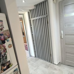 WOJT-KRAZ - Szara, nowoczesna łazienka z płytkami imitującymi marmur, widoczna ażurowa ścianka działowa i drzwi w podobnej tonacji kolorystycznej, lodówka z magnesami w tle.