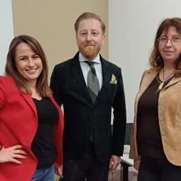 Małgorzata Korólczyk-Rabek - Zespół agencji nieruchomości w Warszawie: kobieta w czerwonej marynarce uśmiecha się, mężczyzna w zielonym garniturze i kobieta w brązowej kurtce stoją obok siebie.