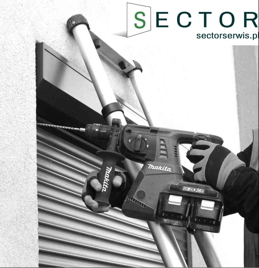 Czarno-białe ujęcie wiertarki udarowej Makita w dłoniach pracownika w rękawicach ochronnych, wiercącego otwór w elewacji obok częściowo opuszczonej, metalowej konstrukcji. W tle widoczna drabina...