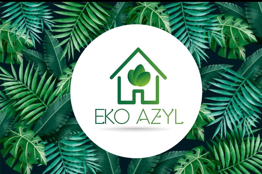 Grafika przedstawia logo 'EKO AZYL' w formie zielonego konturu domu z liśćmi w środku, umieszczone na białym okręgu z tłem z tropikalnych liści.