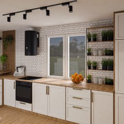 Och.Design - Wizualizacja nowoczesnej kuchni z białymi szafkami, drewnianymi blatami i ścianą z białej cegły, oświetlona reflektorami sufitowymi. Na blacie misa z pomarańczami i zioła w doniczkach na półkach.