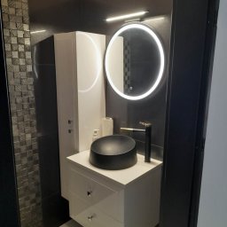 MBUD - Nowoczesna łazienka z czarną umywalką nablatową, podświetlanym lustrem i białą szafką. Ciemne płytki na ścianach, w tym mozaika. Minimalistyczny design.