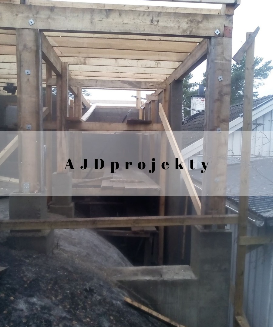 Konstrukcja drewniana w trakcie budowy w Warszawie, widoczne elementy betonowe i drewniane belki, zarys dachu budynku w tle.