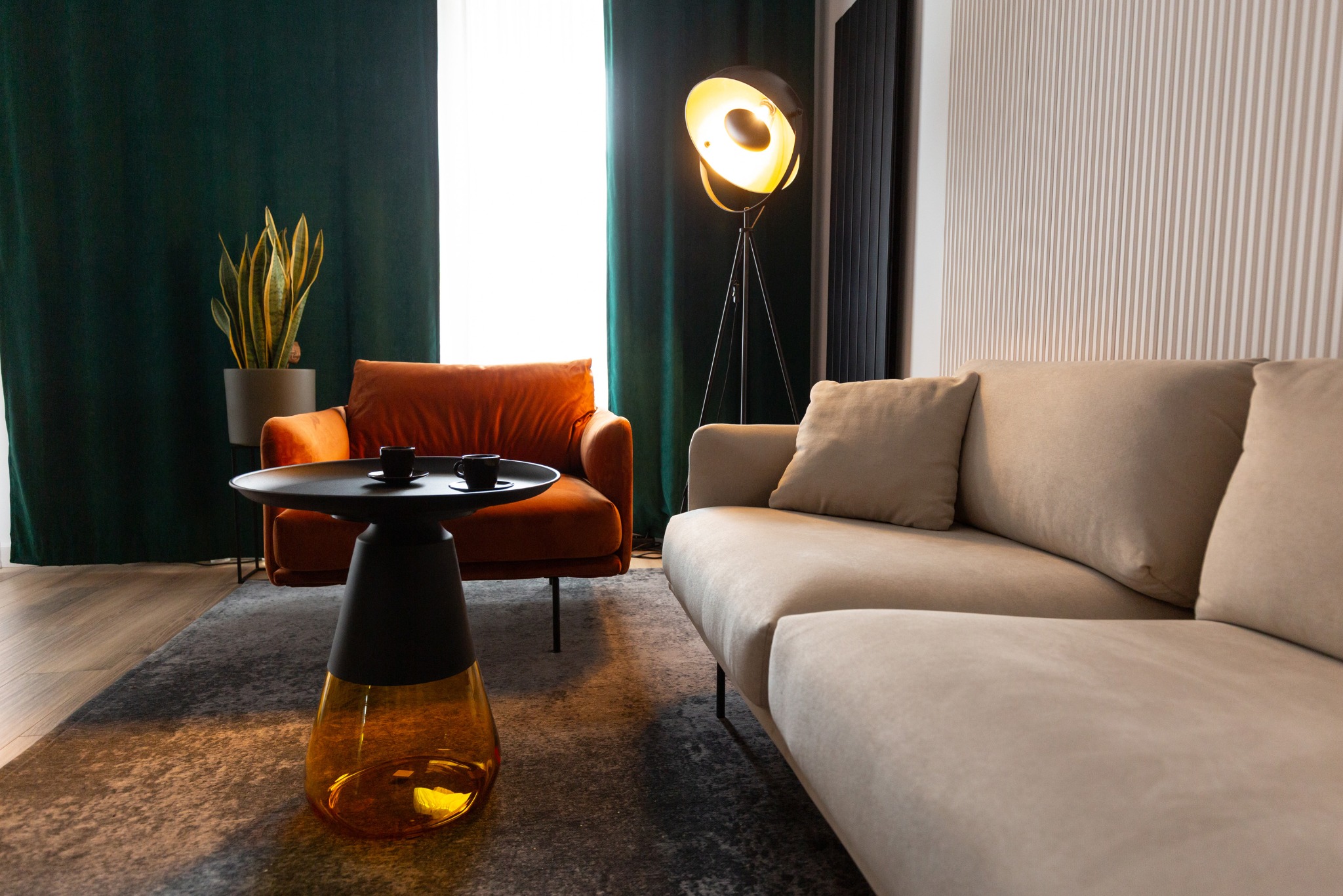 Stylowe wnętrze z sofą w odcieniach beżu, pomarańczowym fotelem i designerskim stolikiem kawowym z dwoma filiżankami na dywanie w nowoczesnym biurze.