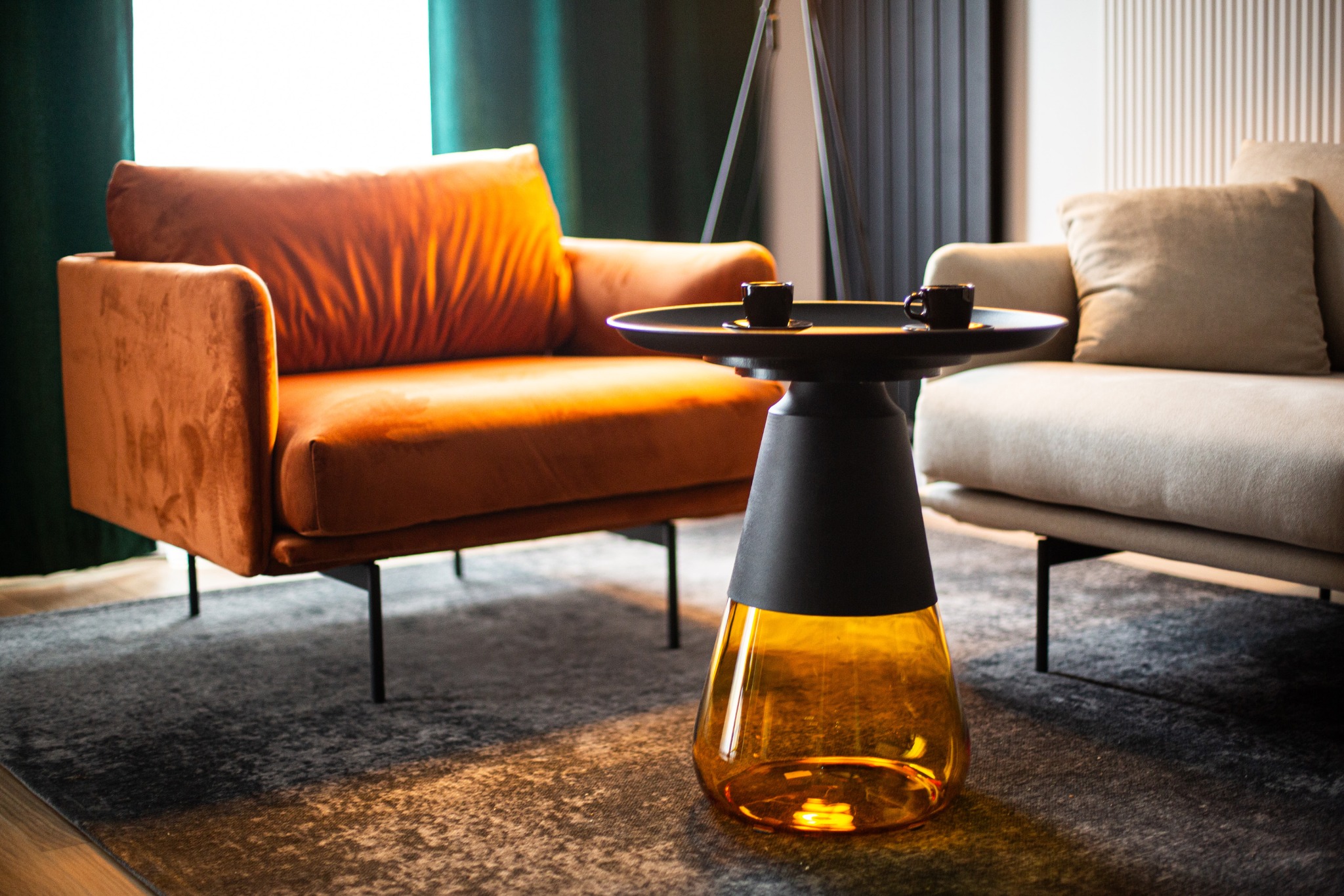 Stylowe wnętrze biurowe: pomarańczowy fotel, stolik z kawą i beżowa sofa na dywanie. Nowoczesne i komfortowe miejsce spotkań.